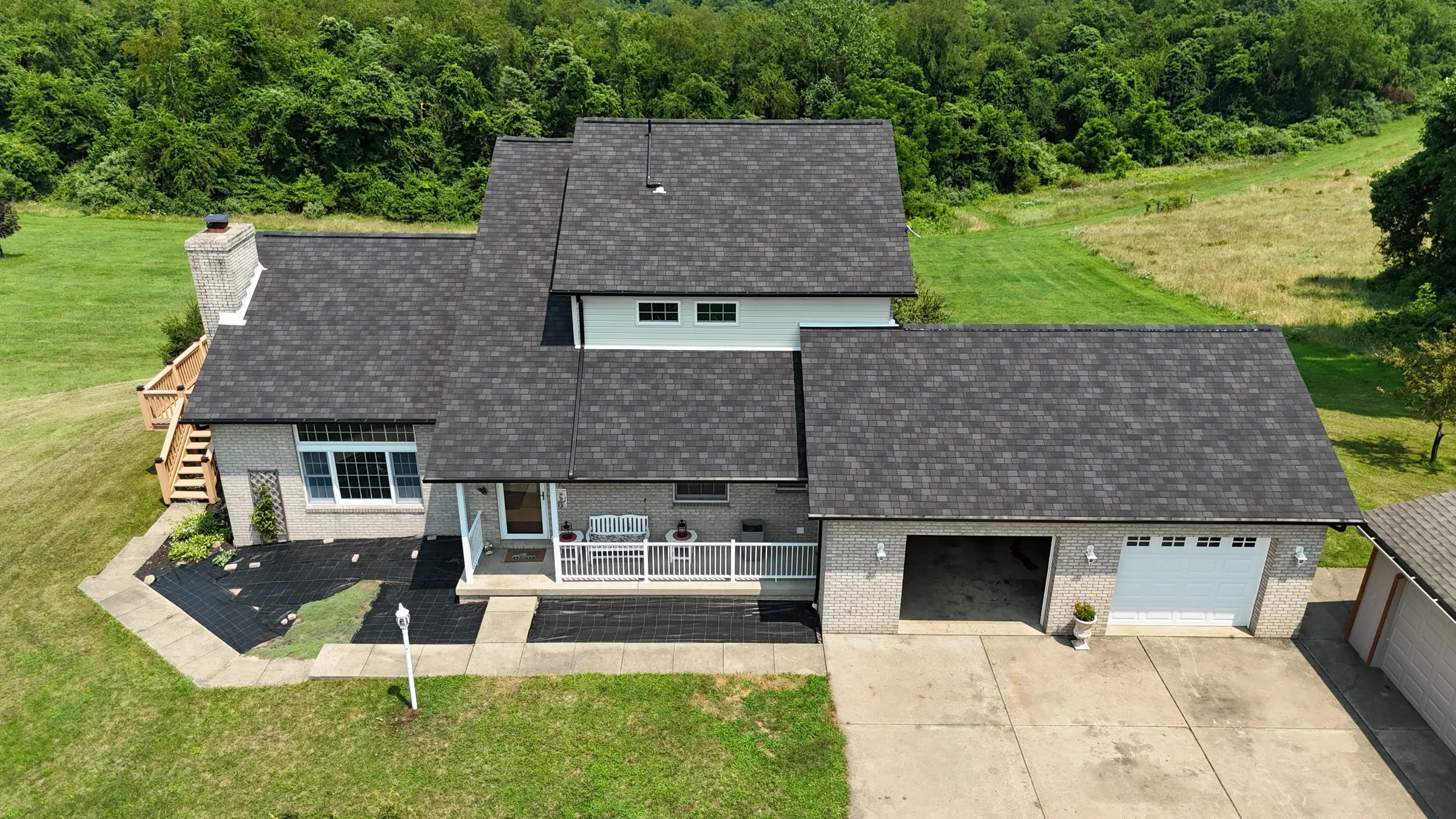 Aerial view of a completed architectural shingle roof on a large home with an attached garage