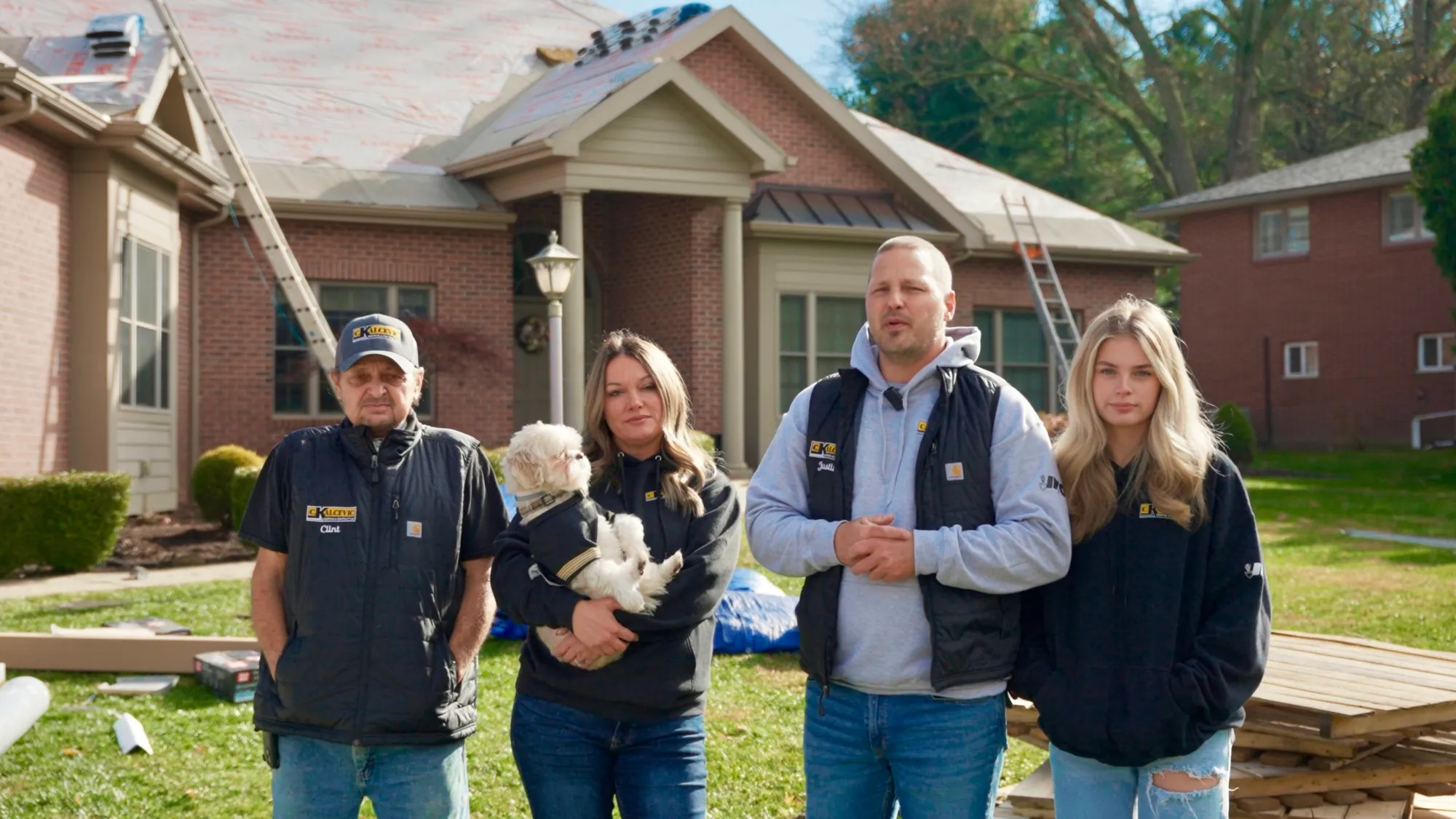 The C. Kalcevic Roofing team standing in front of a job site in branded jackets